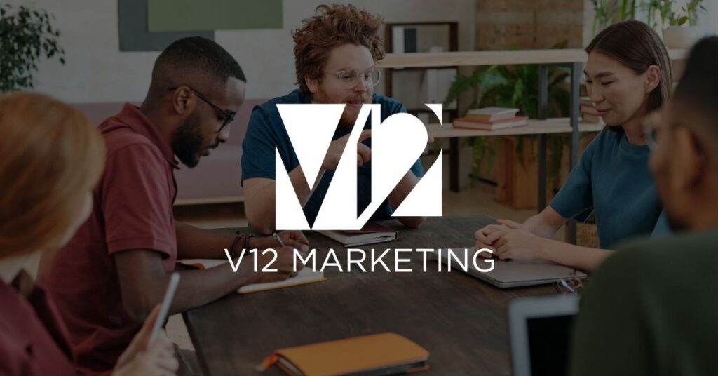Small marketing team talking around a wooden table during a strategy meeting.